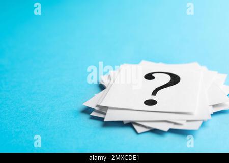 Heap of paper notes with question marks on light blue background, closeup. Space for text Stock Photo