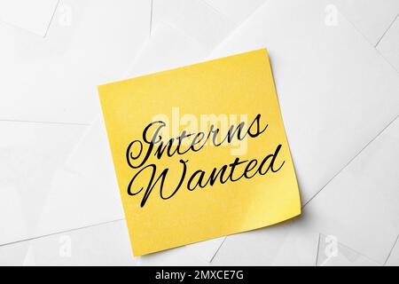 Note with text INTERNS WANTED on paper sheets, top view Stock Photo