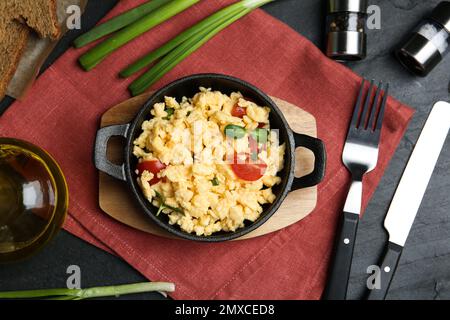 Tasty scrambled eggs served on black table, flat lay Stock Photo