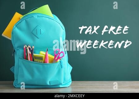 Backpack with school stationery and text TAX FREE WEEKEND written on chalkboard in classroom Stock Photo