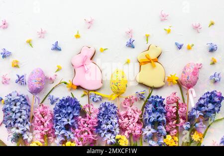 Easter concept with lilac and pink hyacinths, Easter eggs and cookies on white background.  Flat lay, top view. Stock Photo