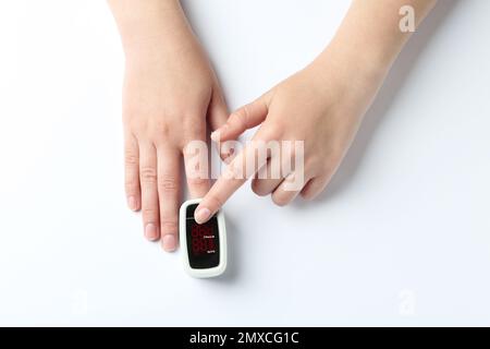 Woman using fingertip pulse oximeter on white background, top view Stock Photo