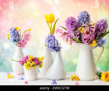 Beautiful spring flowers bouquets in vases on the wooden table.Tulips, narcissus and hyacinths Stock Photo