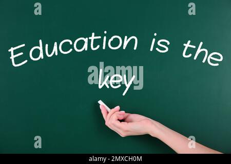 Woman writing phrase Education is the key on chalkboard, closeup. Adult learning Stock Photo