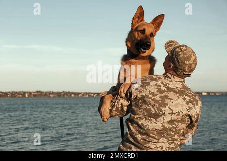 Man in military uniform with German shepherd dog outdoors Stock Photo