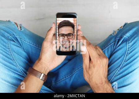 Man using smartphone with facial recognition system indoors, top view. Biometric verification Stock Photo