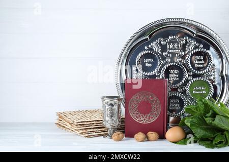 Symbolic Pesach (Passover Seder) items on white wooden table. Space for text Stock Photo