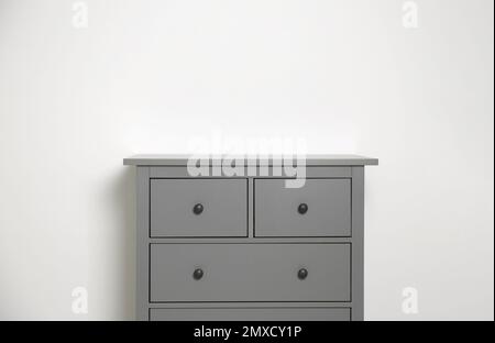 Grey chest of drawers on light background. Space for text Stock Photo ...