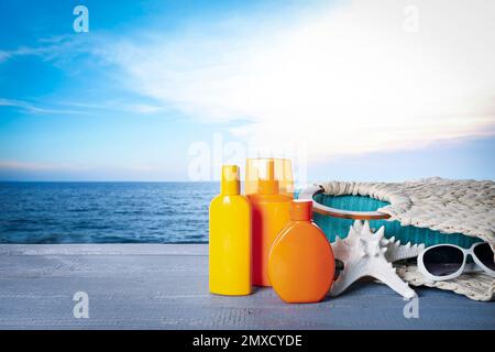Set of sun protection products and stylish accessories on wooden table near sea. Space for text Stock Photo