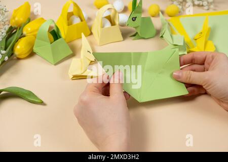Handicrafts from paper for Easter - origami, making figurines of Easter bunnies, hands close-up Stock Photo