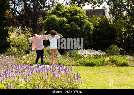 Happy diverse couple having fun, dancing in sunny garden, copy space Stock Photo