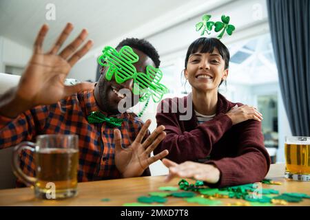 Portrait of happy multiracial friends with shamrock novelty glasses and headband at st patrick's day Stock Photo