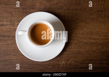 White cup of espresso on wooden table, top view Stock Photo
