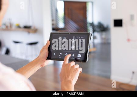 Hands of biracial man at home using tablet with smart home interface on screen Stock Photo