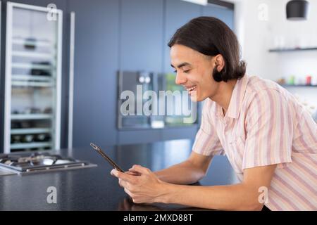 Happy biracial man using tablet in kitchen Stock Photo