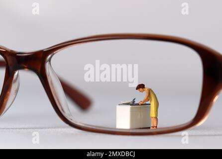 The concept of social prejudice against women. Business concept with glasses and miniature people. Stock Photo