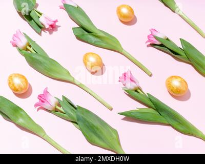 Flatlay with a pattern of golden easter eggs and tulips on pink background Stock Photo