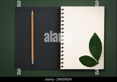 top view open notebook with beige pencil white paper and black copy space on dark green background.idea for text writing. Stock Photo