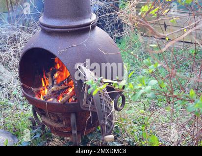 Fire burning in a chimenea. Chimenea stove in a garden to either keep warm or cook on. Stock Photo