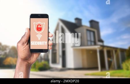 Alarm system. African-American man using phone outdoors, space for text Stock Photo