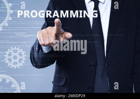 Businessman pointing at word PROGRAMMING on virtual screen, closeup Stock Photo