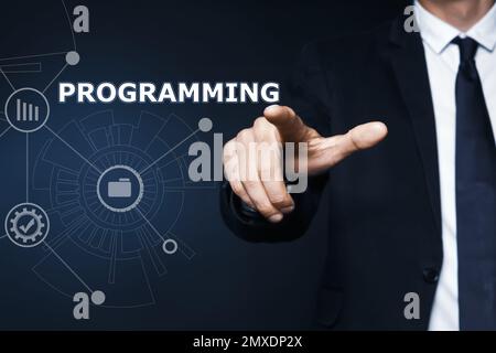 Businessman pointing at word PROGRAMMING on virtual screen, closeup Stock Photo