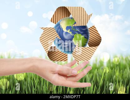 Woman with illustration of Earth and recycling symbol in hand, closeup Stock Photo