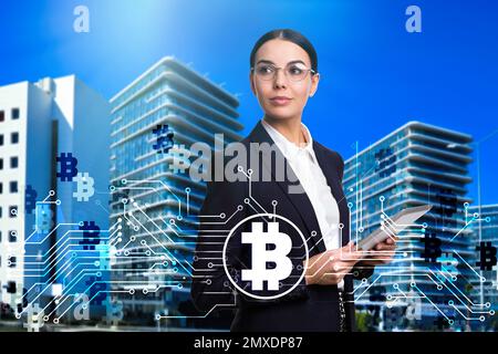 Fintech concept. Scheme with bitcoin symbols and businesswoman using tablet on cityscape background Stock Photo