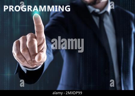 Businessman pointing at word PROGRAMMING on virtual screen, closeup Stock Photo