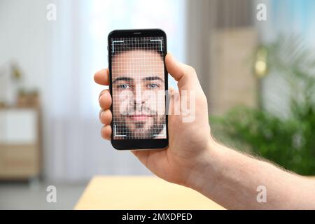 Man using smartphone with facial recognition system indoors, closeup. Biometric verification Stock Photo
