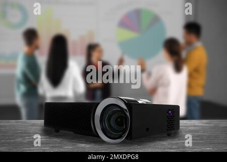 Modern video projector and blurred people on background Stock Photo