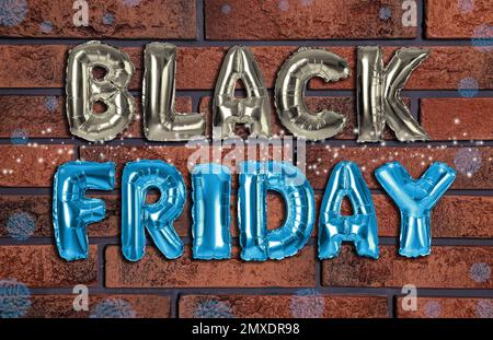 Phrase BLACK FRIDAY made of foil balloon letters against brick wall Stock Photo
