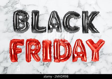 Phrase BLACK FRIDAY made of foil balloon letters on white marble background Stock Photo