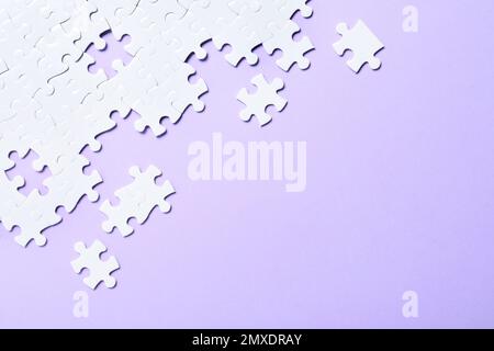 Blank white puzzle pieces on violet background, flat lay. Space for text Stock Photo