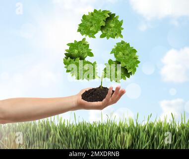 Man holding fertile soil in hand and recycling symbol, closeup Stock Photo