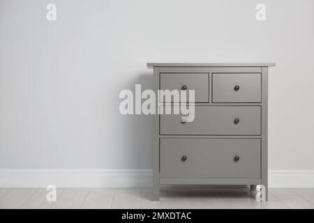 Grey chest of drawers near light wall. Space for text Stock Photo