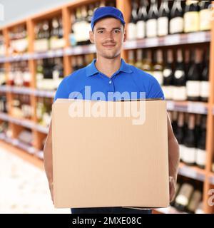 Man wearing uniform with cardboard box in store. Wholesale market Stock Photo