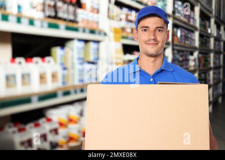 Man wearing uniform with cardboard box in store. Wholesale market Stock Photo