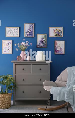 Beautiful artworks and chest of drawers in stylish room. Interior design Stock Photo