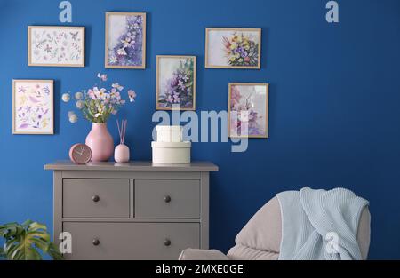 Beautiful artworks and chest of drawers in stylish room. Interior design Stock Photo