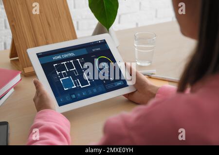 Energy efficiency home control system. Woman using tablet to set indoor temperature, closeup Stock Photo