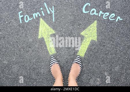 Life choice. Woman on road near arrows with directions to family and career, top view Stock Photo
