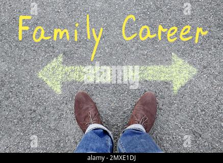 Life choice. Man on road near arrows with directions to family and career, top view Stock Photo