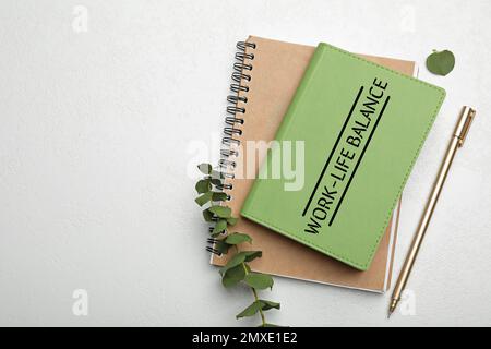Work-life balance concept. Stylish notebooks, pen and branch on white table, flat lay Stock Photo