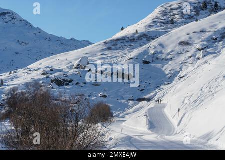 2 walkers on a walking trail in the French ski resort of Les Menuires heading up a path towards Lac de Lou Stock Photo