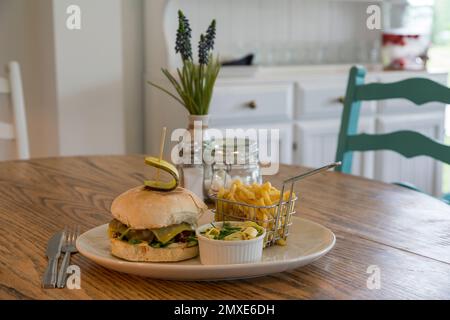 Cafe interior hamburger with chips and coleslaw served on a white plate Stock Photo