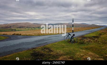 Road bike leaned up against a black and white signpost to Whelpo with Blencathra in the background. Lake District National Park, Cumbria, England, UK Stock Photo