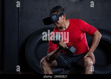 A closeup of a Mexican man doing a weight training exercise by using a dumbbell and virtual reality VR goggles Stock Photo
