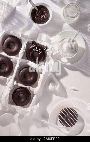 Glazed chocolate donuts and cup of cappuccino on stone background. Top view. Flat lay composition Stock Photo
