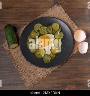 Top view of a plate with fried egg and sliced zucchini, on a jute placemat Stock Photo